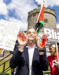 protester wearing a mask of Tony Blair wearing handcuffs and with blood on his hands